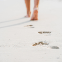 Woman walking on beach leaving footsteps